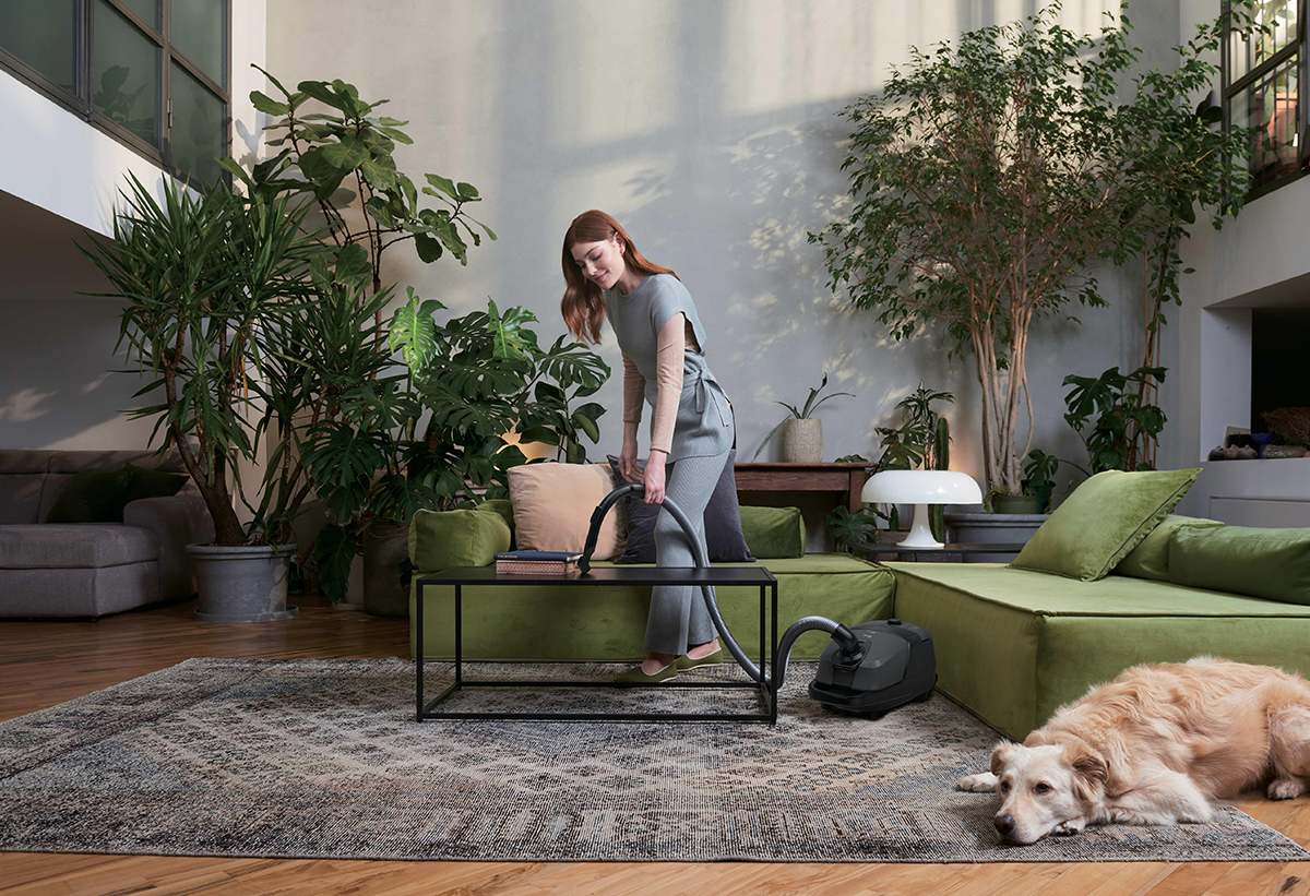 Απεικονίζεται γυναίκα να καθαρίζει σε σαλόνι.